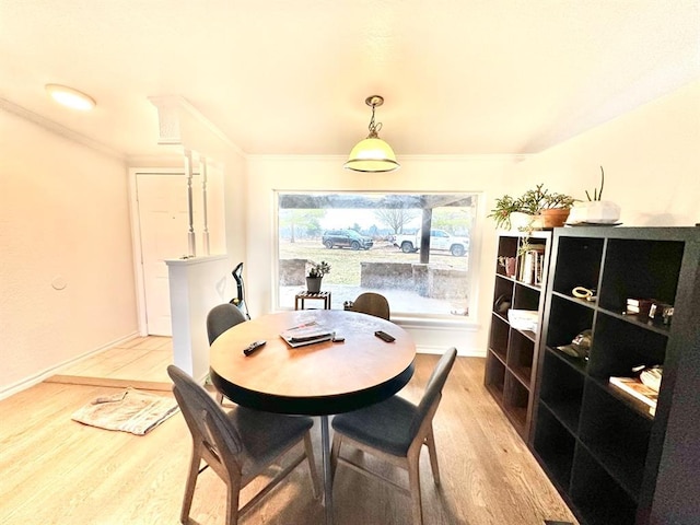 dining space with crown molding, baseboards, and light wood finished floors