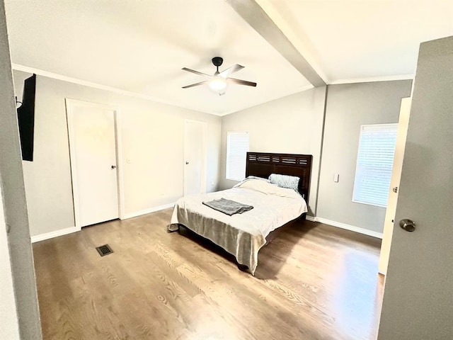 bedroom featuring baseboards, vaulted ceiling with beams, wood finished floors, and ornamental molding