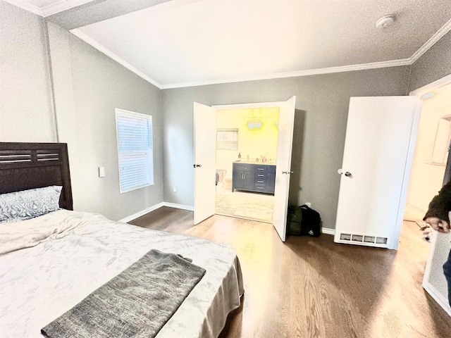 bedroom featuring baseboards, wood finished floors, and crown molding