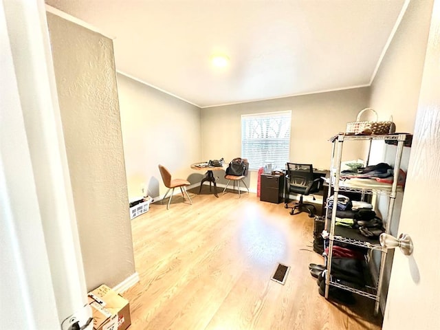 office area featuring baseboards, visible vents, crown molding, and wood finished floors