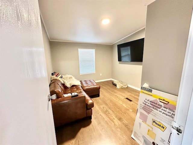 living room with baseboards, visible vents, wood finished floors, and ornamental molding