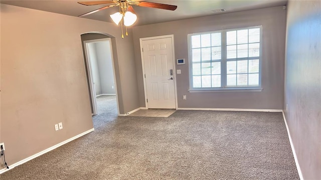 foyer entrance with baseboards, arched walkways, ceiling fan, and carpet