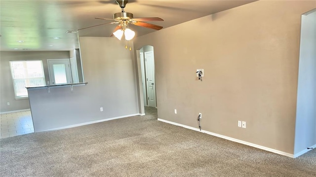 empty room with arched walkways, ceiling fan, and carpet floors