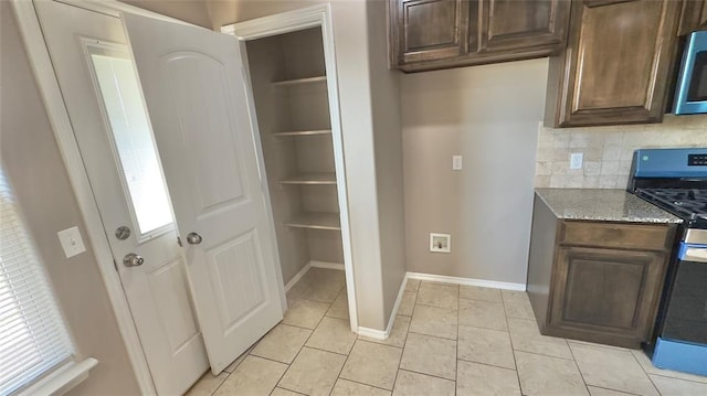 kitchen with baseboards, dark brown cabinets, stainless steel appliances, and tasteful backsplash