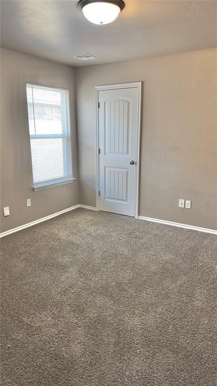 spare room featuring visible vents, carpet flooring, and baseboards