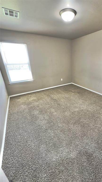 carpeted empty room with visible vents and baseboards