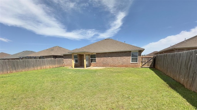 rear view of property with a yard, brick siding, and a fenced backyard