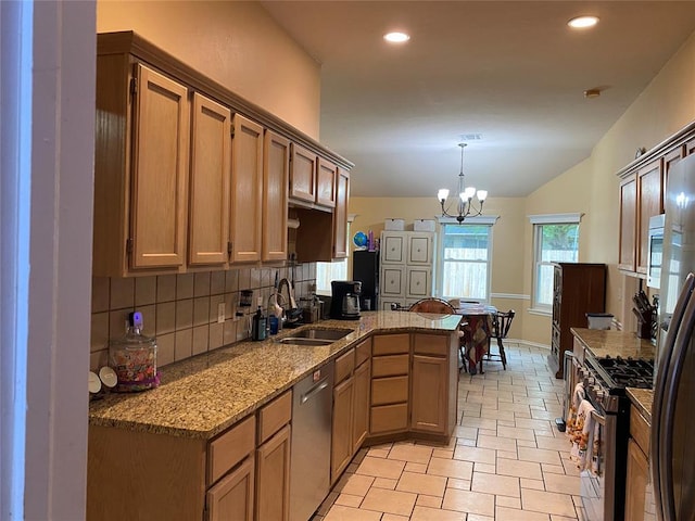 kitchen with light stone countertops, a sink, stainless steel appliances, backsplash, and a peninsula