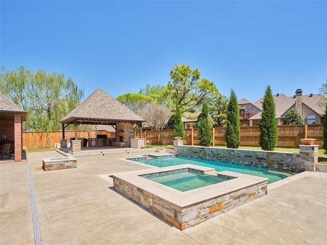 view of pool with a fenced backyard, a patio area, an in ground hot tub, a gazebo, and an outdoor stone fireplace