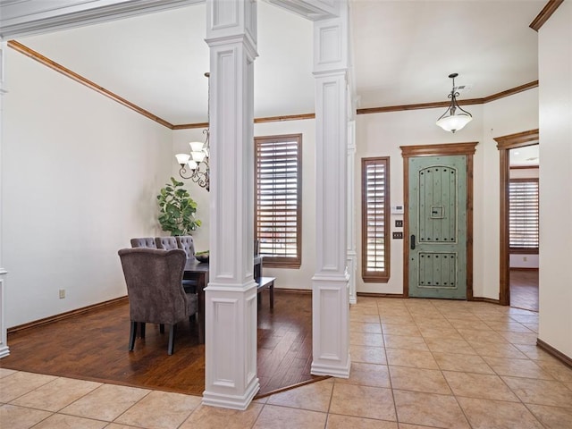 foyer featuring ornate columns, crown molding, light tile patterned floors, and baseboards