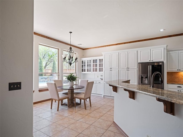 dining space featuring a notable chandelier, baseboards, ornamental molding, light tile patterned floors, and visible vents