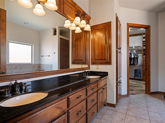 bathroom featuring double vanity, a sink, tile patterned flooring, and baseboards