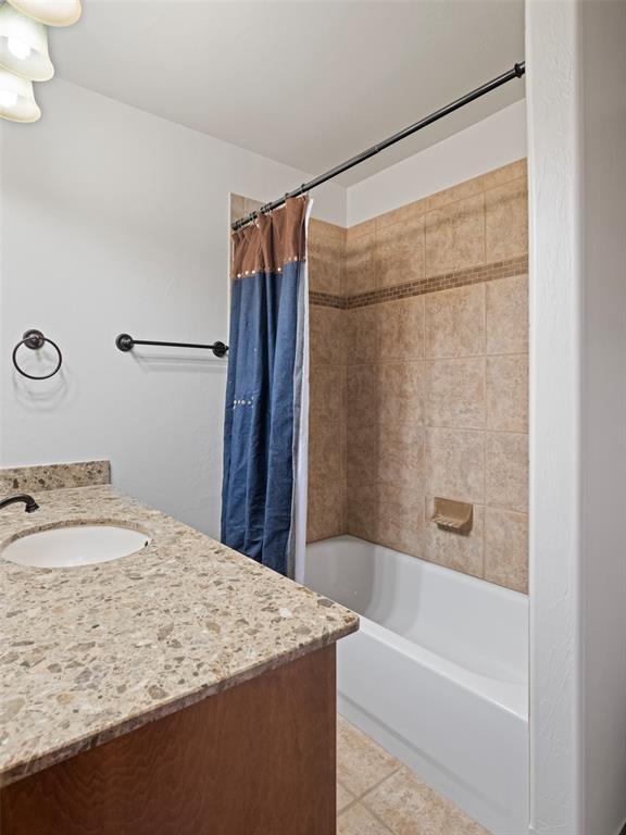 full bath featuring tile patterned floors, vanity, and shower / bath combination with curtain