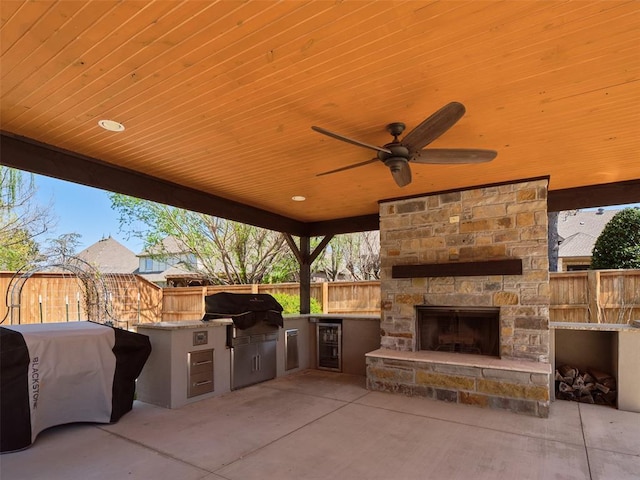 4200 Slate Bridge Rd, Edmond, OK 73034 - view of patio featuring wine cooler, exterior kitchen, ceiling fan, and an outdoor stone fireplace