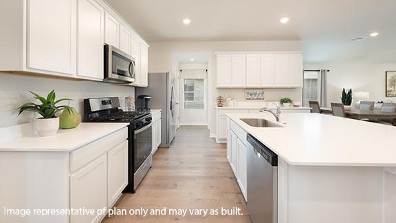5510 Windstone Ln, Norman, OK 73072 - kitchen with appliances with stainless steel finishes, a sink, light wood-style floors, recessed lighting, and light countertops