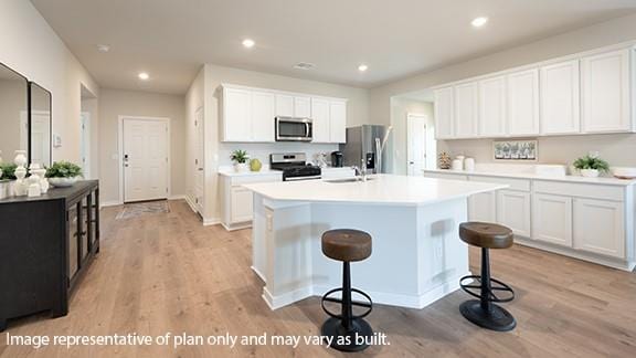 5510 Windstone Ln, Norman, OK 73072 - kitchen featuring appliances with stainless steel finishes, light wood-style floors, an island with sink, light countertops, and recessed lighting