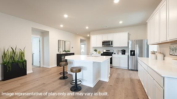 5510 Windstone Ln, Norman, OK 73072 - kitchen with stainless steel appliances, light wood-style floors, a kitchen island with sink, white cabinets, and light countertops