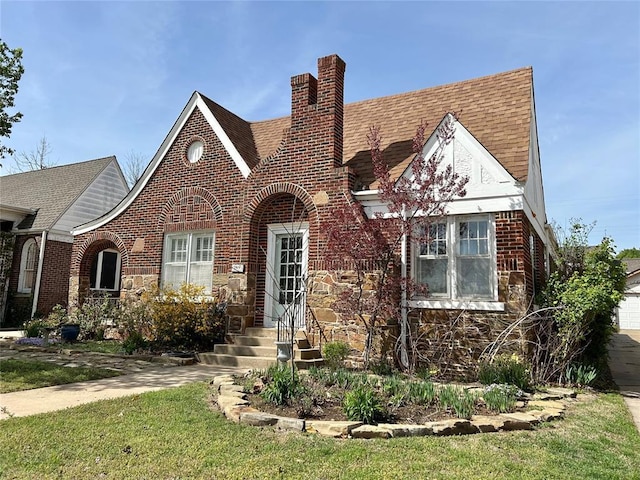 1909 N Gatewood Ave, Oklahoma City, OK 73106 - tudor-style house featuring entry steps, roof with shingles, stone siding, brick siding, and a chimney