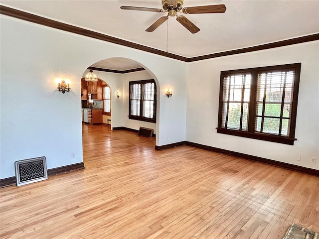 1909 N Gatewood Ave, Oklahoma City, OK 73106 - unfurnished room with visible vents, baseboards, arched walkways, light wood-style floors, and crown molding