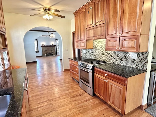 1909 N Gatewood Ave, Oklahoma City, OK 73106 - kitchen with light wood-type flooring, dark stone counters, ceiling fan, arched walkways, and stainless steel range with gas stovetop