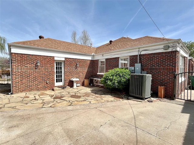 1909 N Gatewood Ave, Oklahoma City, OK 73106 - back of property with brick siding, roof with shingles, a patio, and central air condition unit