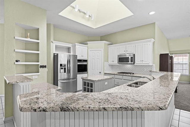 4113 Annalane Dr, Norman, OK 73072 - kitchen featuring open shelves, a sink, light stone counters, a peninsula, and appliances with stainless steel finishes