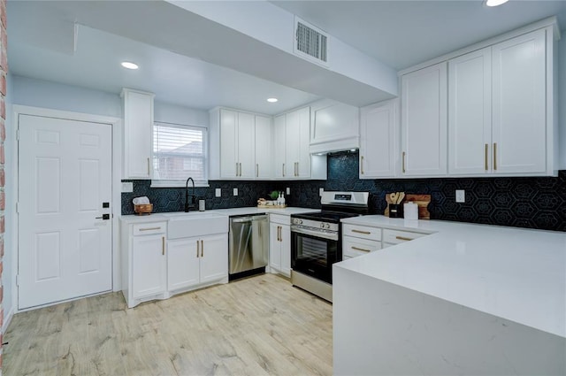 kitchen featuring a sink, white cabinetry, stainless steel appliances, visible vents, and light wood-style floors