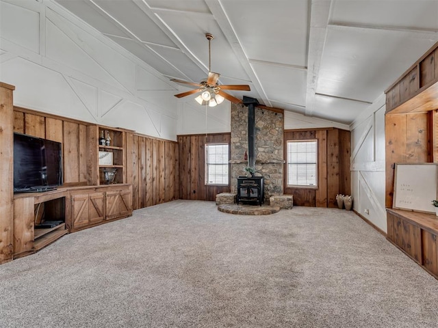 27704 S County Line Ave, Blanchard, OK 73010 - unfurnished living room featuring wood walls, vaulted ceiling, a wood stove, carpet flooring, and ceiling fan
