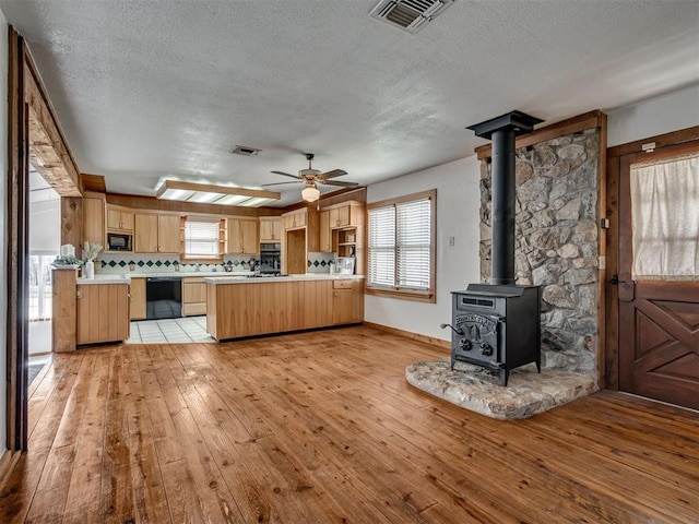 27704 S County Line Ave, Blanchard, OK 73010 - kitchen featuring a textured ceiling, black appliances, light wood finished floors, a peninsula, and visible vents