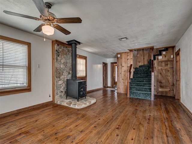 27704 S County Line Ave, Blanchard, OK 73010 - unfurnished living room with stairway, a wood stove, visible vents, wood-type flooring, and ceiling fan