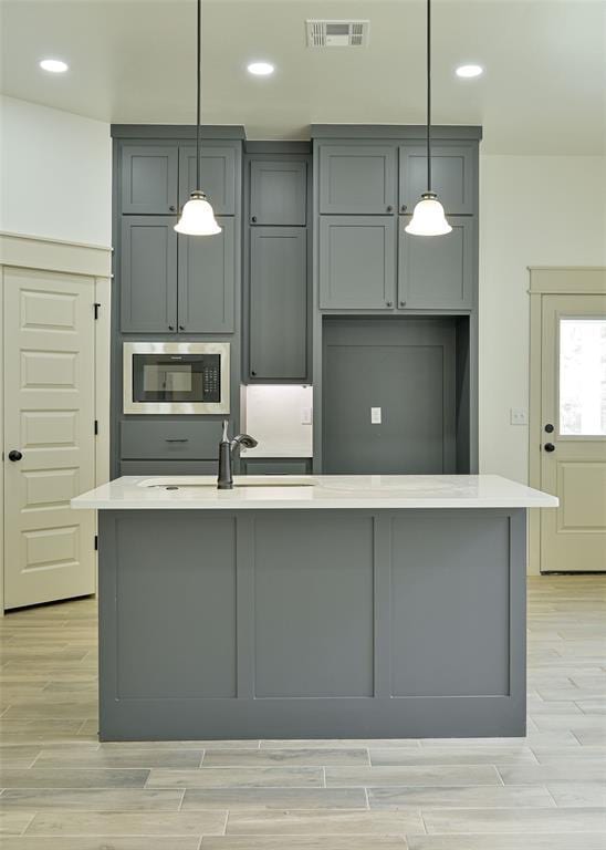 128 E 7th St, Arcadia, OK 73007 - kitchen with stainless steel microwave, gray cabinets, a sink, light countertops, and recessed lighting