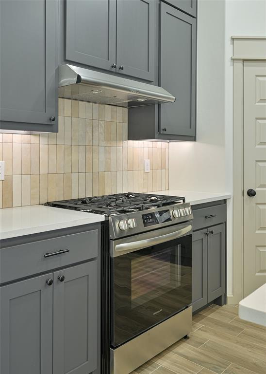128 E 7th St, Arcadia, OK 73007 - kitchen featuring gas range, under cabinet range hood, gray cabinets, and light countertops