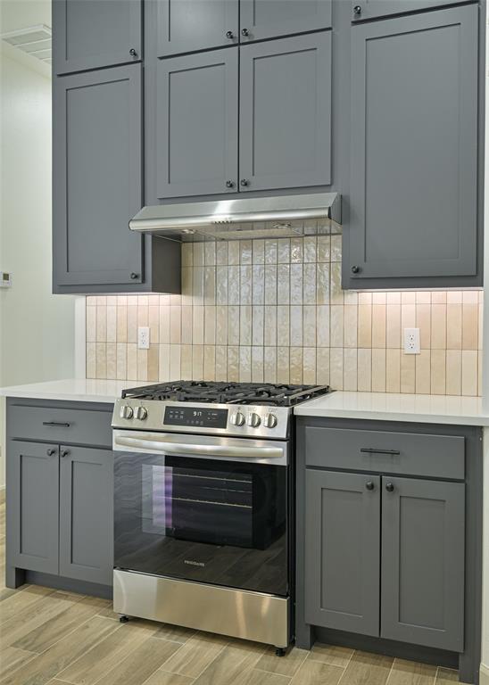 128 E 7th St, Arcadia, OK 73007 - kitchen featuring gas range, gray cabinets, under cabinet range hood, and light countertops
