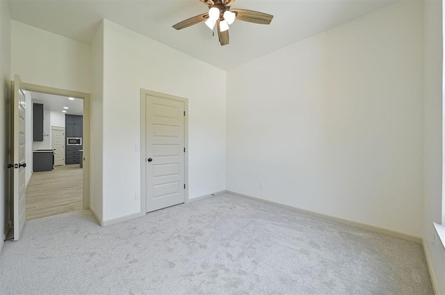 128 E 7th St, Arcadia, OK 73007 - unfurnished bedroom featuring light carpet, baseboards, and a ceiling fan