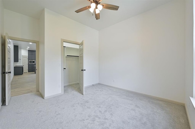 128 E 7th St, Arcadia, OK 73007 - unfurnished bedroom with light colored carpet, baseboards, ceiling fan, and a spacious closet