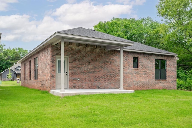 128 E 7th St, Arcadia, OK 73007 - back of house featuring a yard, brick siding, and roof with shingles