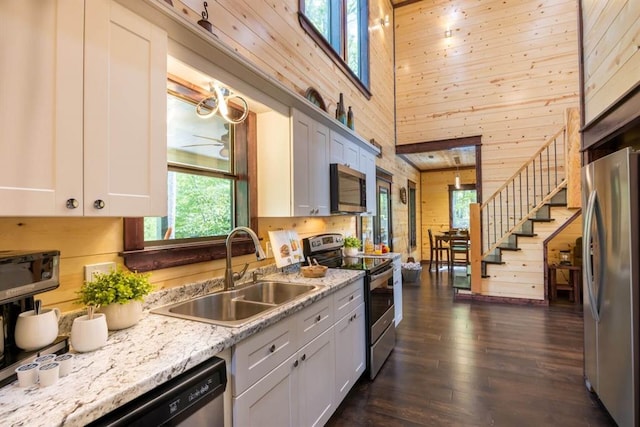 167 Penner Rd, Broken Bow, OK 74728 - kitchen with stainless steel appliances, dark wood finished floors, a sink, a towering ceiling, and wooden walls