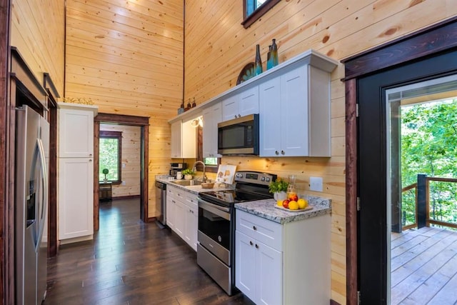 167 Penner Rd, Broken Bow, OK 74728 - kitchen with wood walls, a sink, dark wood-style floors, white cabinets, and appliances with stainless steel finishes
