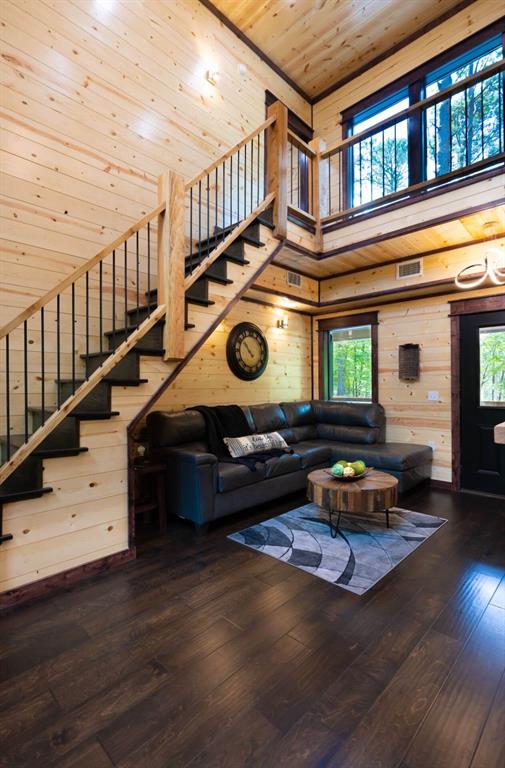 167 Penner Rd, Broken Bow, OK 74728 - living room featuring stairs, hardwood / wood-style floors, wooden ceiling, wooden walls, and a wealth of natural light