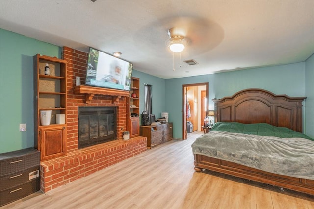 103 W Thompson Dr, Kingfisher, OK 73750 - bedroom with a brick fireplace, visible vents, a ceiling fan, and wood finished floors