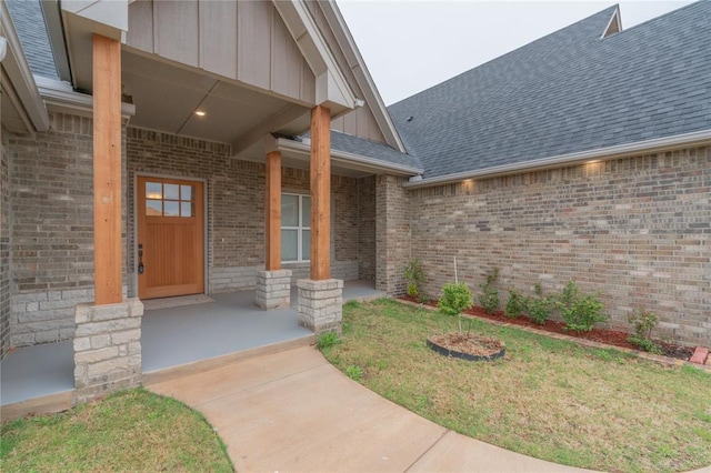 doorway to property featuring covered porch, board and batten siding, and roof with shingles