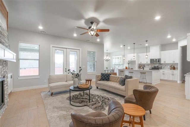 living room featuring light wood finished floors, a fireplace, visible vents, ceiling fan, and recessed lighting