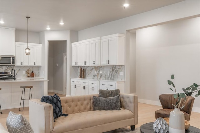 living area with baseboards, light wood-style flooring, and recessed lighting