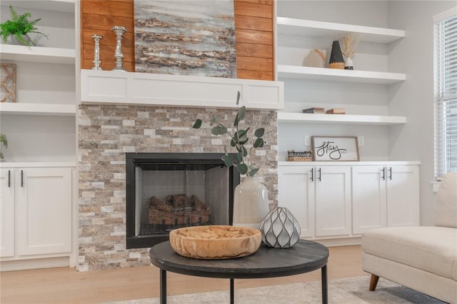 living room featuring a fireplace, built in shelves, and light wood-style floors