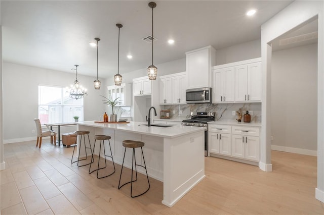 kitchen with a sink, stainless steel appliances, visible vents, white cabinets, and decorative backsplash