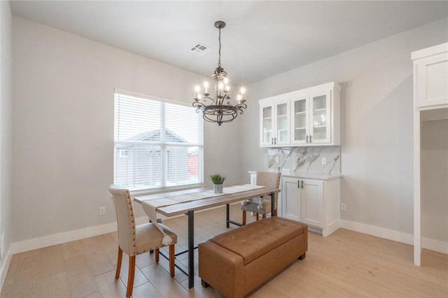 dining space featuring an inviting chandelier, light wood-style flooring, baseboards, and visible vents