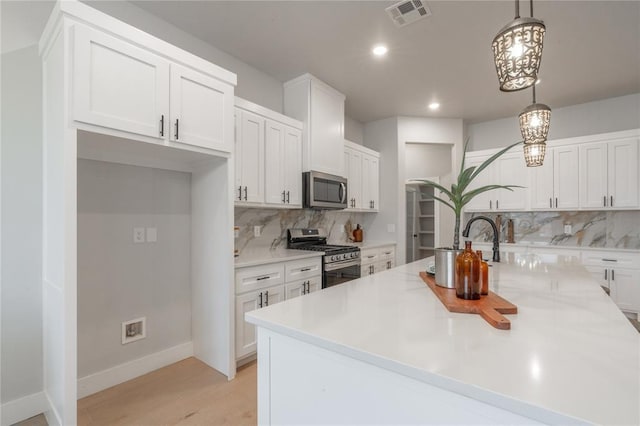 kitchen featuring visible vents, light countertops, white cabinets, and stainless steel appliances