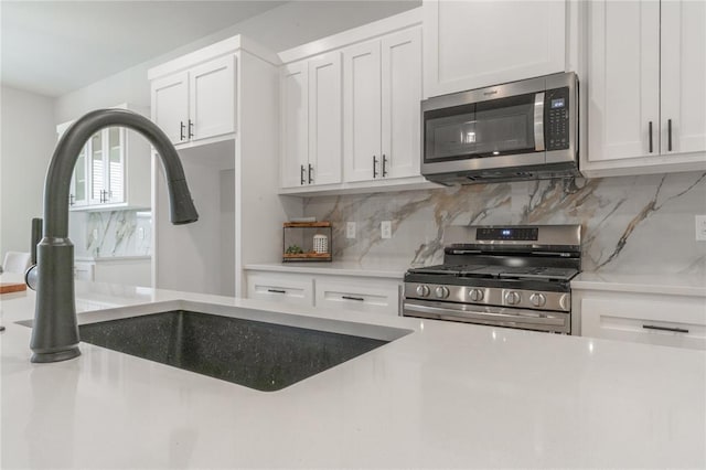 kitchen featuring white cabinetry, a sink, tasteful backsplash, and appliances with stainless steel finishes