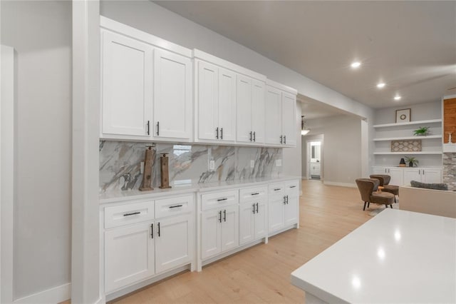 kitchen with light countertops, white cabinets, backsplash, and light wood-type flooring