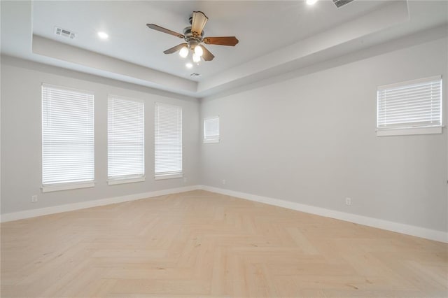 empty room with visible vents, baseboards, recessed lighting, a ceiling fan, and a tray ceiling